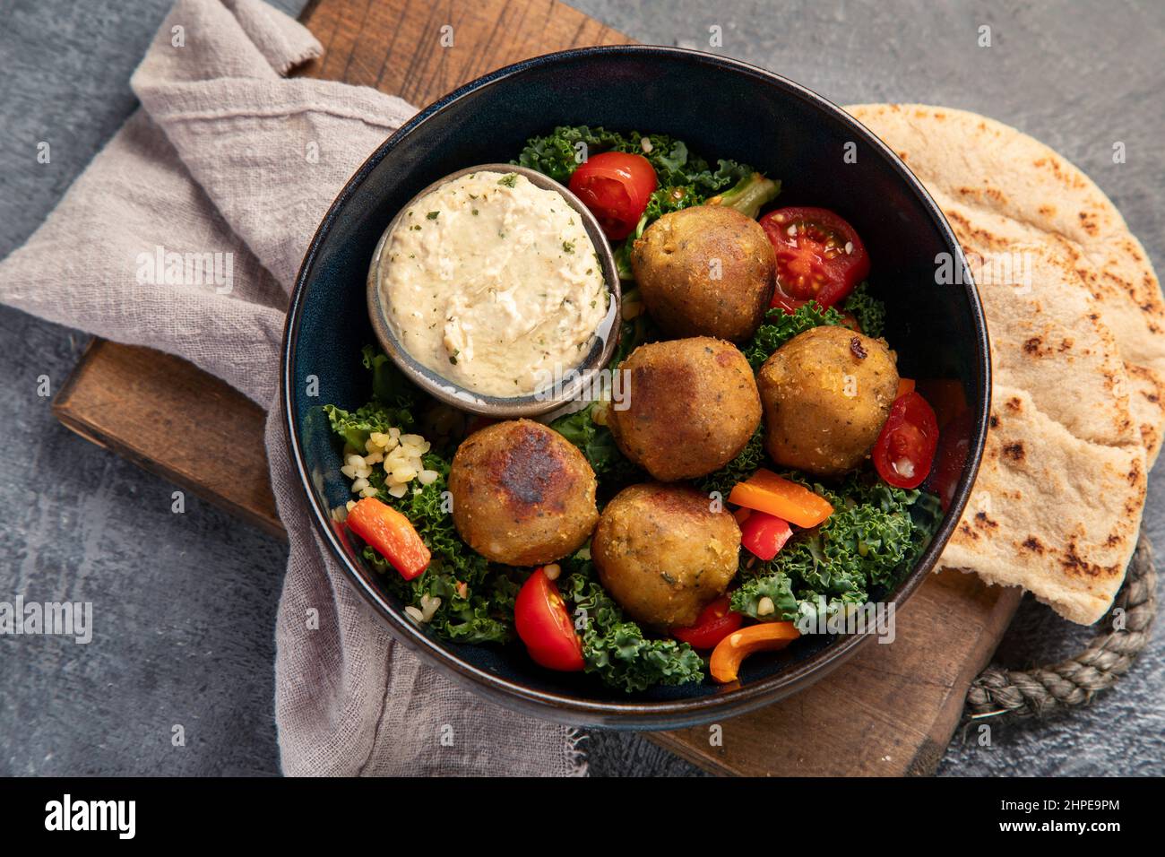 Falafel con hummus su sfondo scuro. Concetto di dieta mediterranea. Disposizione piatta, vista dall'alto Foto Stock
