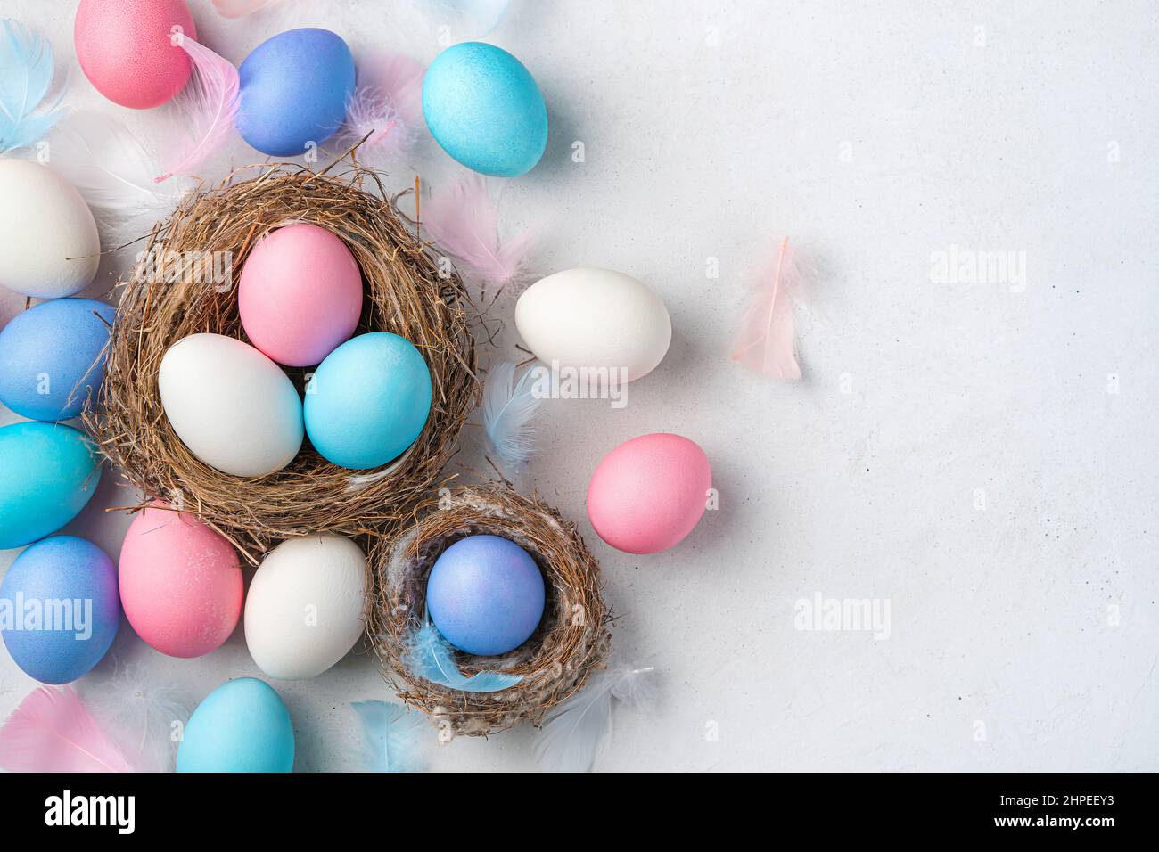 Uova di Pasqua e nidi su sfondo grigio. Vista dall'alto, spazio di copia. Foto Stock