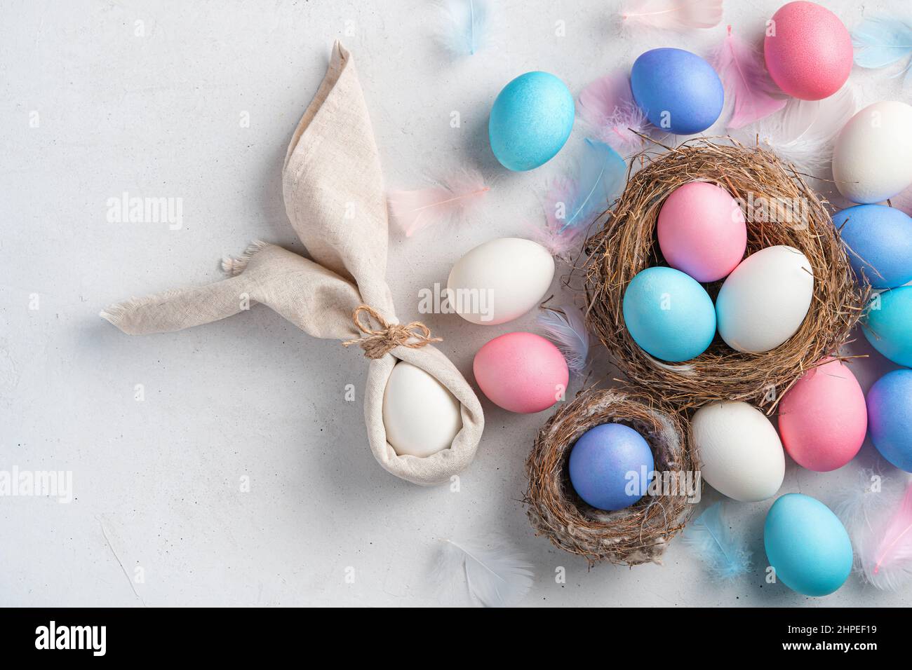 Buona Pasqua. Uova di Pasqua e un coniglio da un tovagliolo su sfondo grigio. Vista dall'alto, spazio di copia. Foto Stock