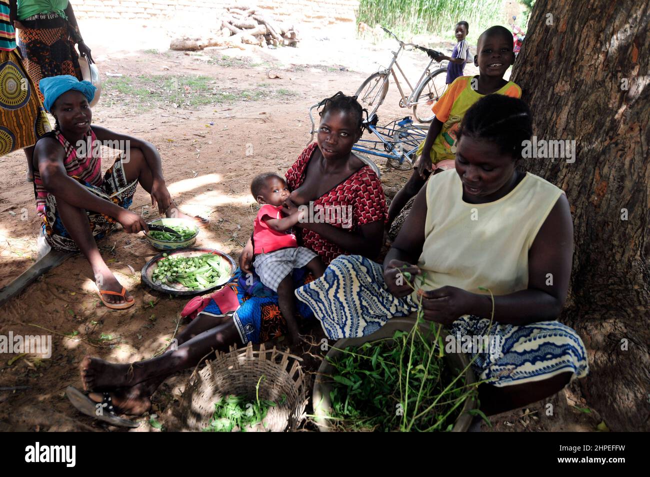 Una donna del Burkinabe che allattava il suo bambino in un mercato locale nel Burkina Faso centrale. Foto Stock