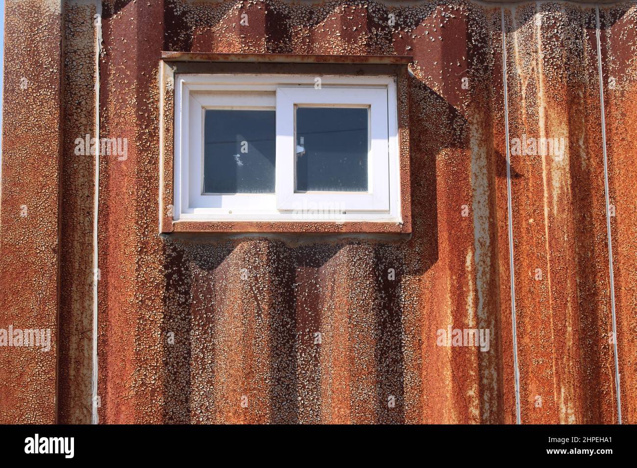 Piccola finestra sulla casa contenitore di spedizione arrugginita Foto Stock