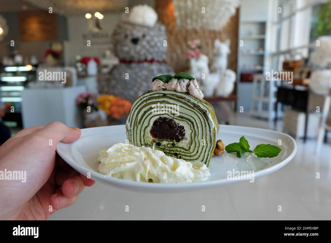 Primo piano torta di tè verde Matcha decorata con fagioli rossi schiacciati, panna montata e noci Foto Stock