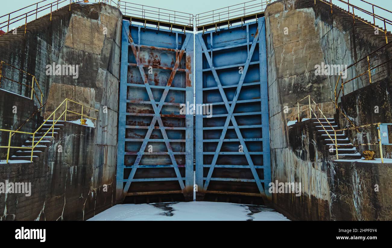 Alla base della vecchia diga sull'acqua queste porte sono alte sulle acque ghiacciate Foto Stock