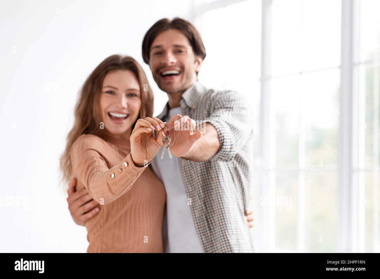 Allegro soddisfatto eccitato millenario caucasico maschio e femmina celebrare l'acquisto proprio appartamento, mostra chiavi Foto Stock