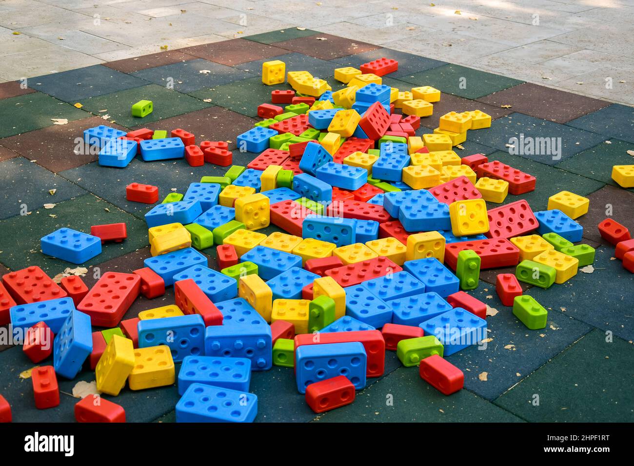 Grandi blocchi di plastica multicolore sono sparsi intorno al parco giochi. Giochi all'aperto per bambini. Primo piano. Spazio di copia. Messa a fuoco selettiva. Foto Stock
