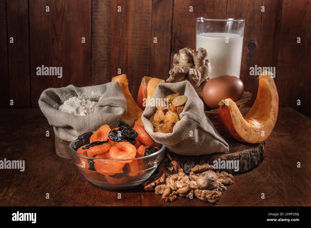 zucca e ingredienti per casseruola di zucca con noci e frutta secca su sfondo scuro Foto Stock