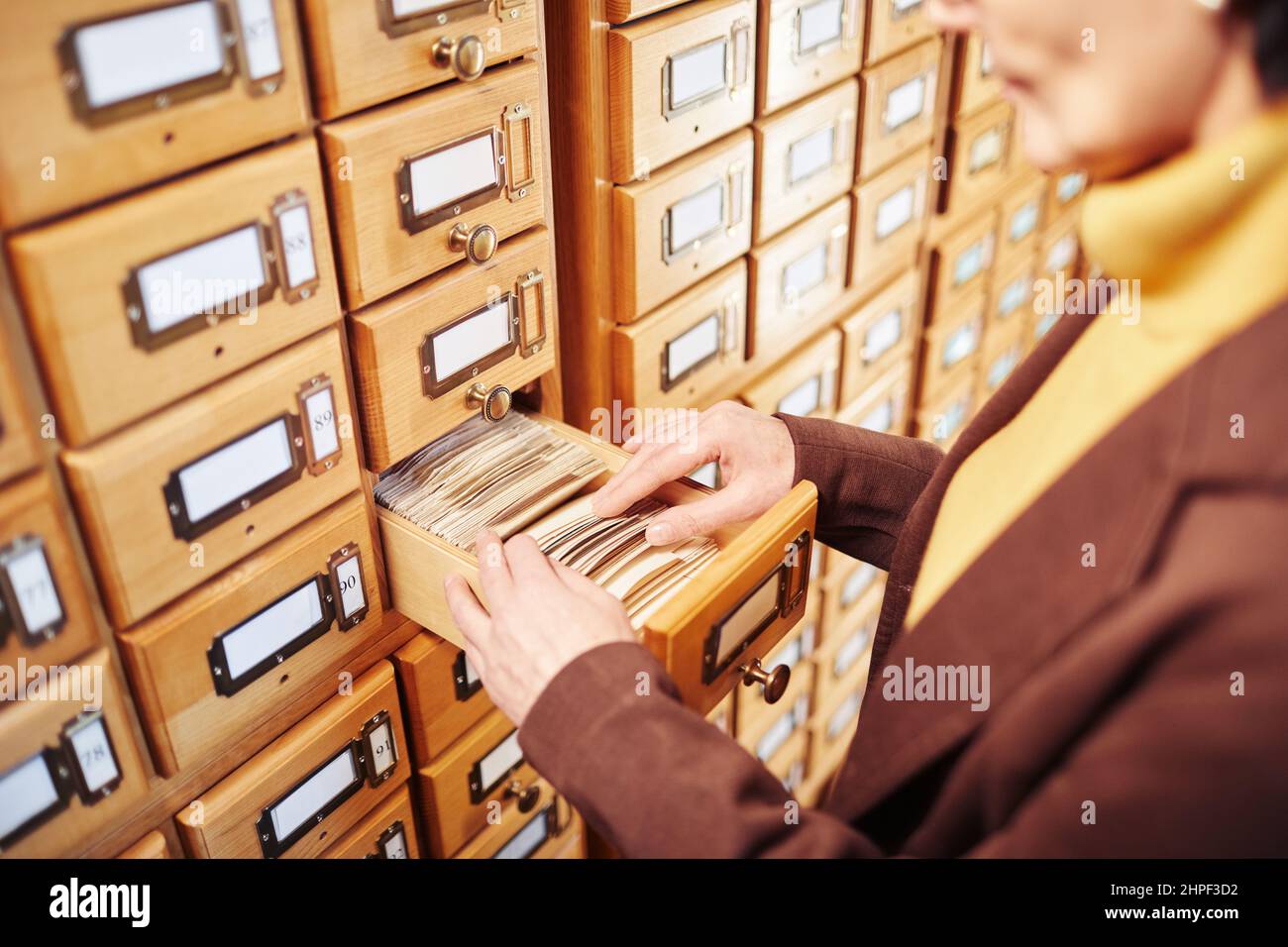 Primo piano di donna bibliotecaria ricerca libro in libreria catalogo cabinet, spazio copia Foto Stock