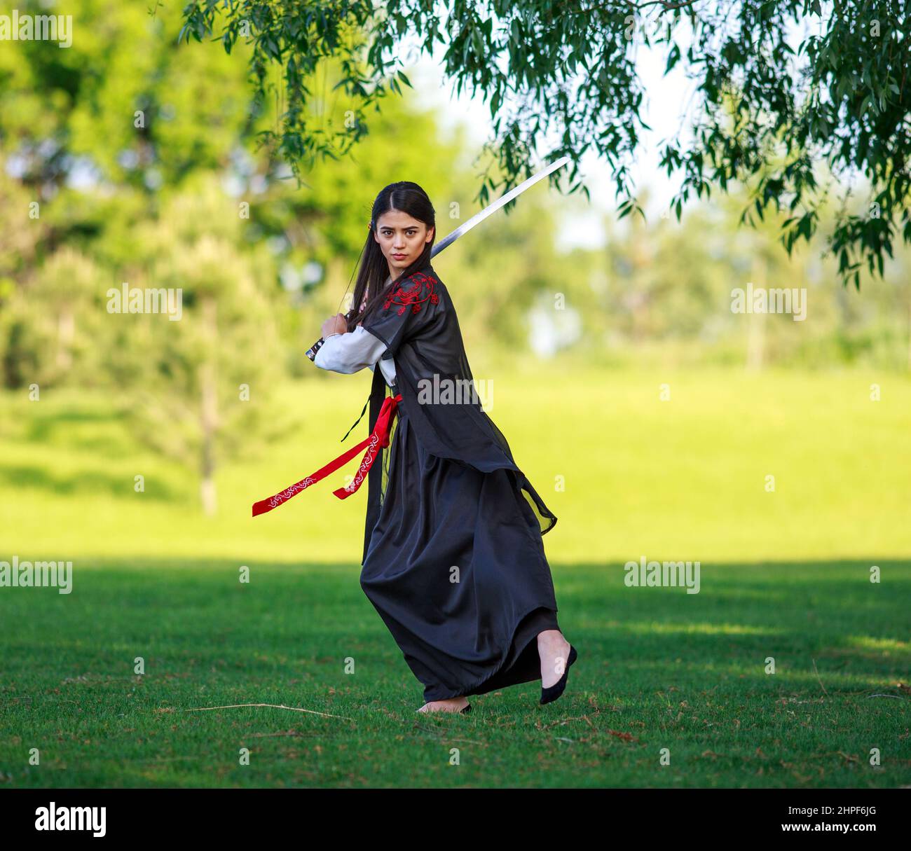 Giovane donna asiatica in kimono tradizionale treni tecniche di combattimento con la spada katana, samurai guerriero ragazza Foto Stock