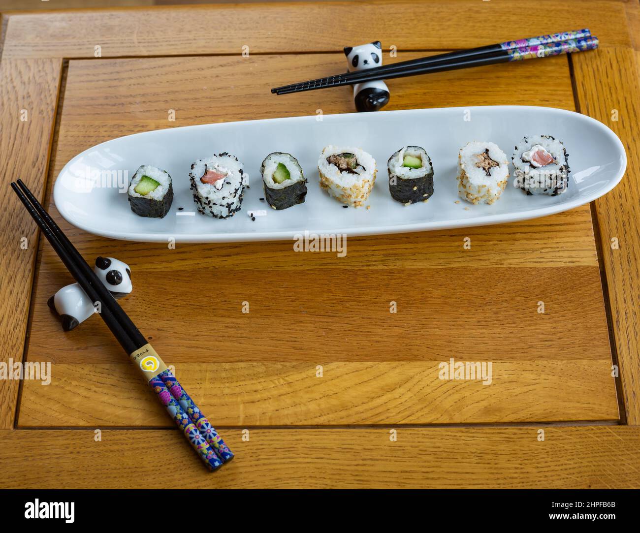 Sushi fresco su un piatto da portata bianco con due paia di bacchette  appoggiate su porta panda Foto stock - Alamy