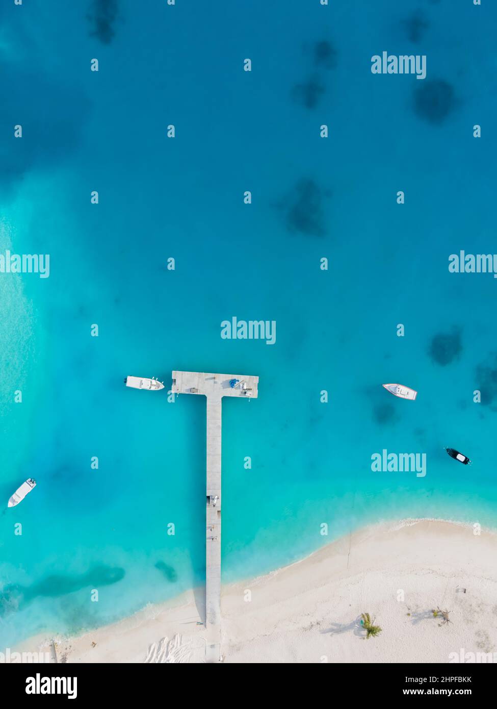 Spiaggia di sabbia bianca e molo del porto con acque blu e turchesi trasparenti, vista dall'alto dal drone sull'isola tropicale delle Maldive. Bella va Foto Stock