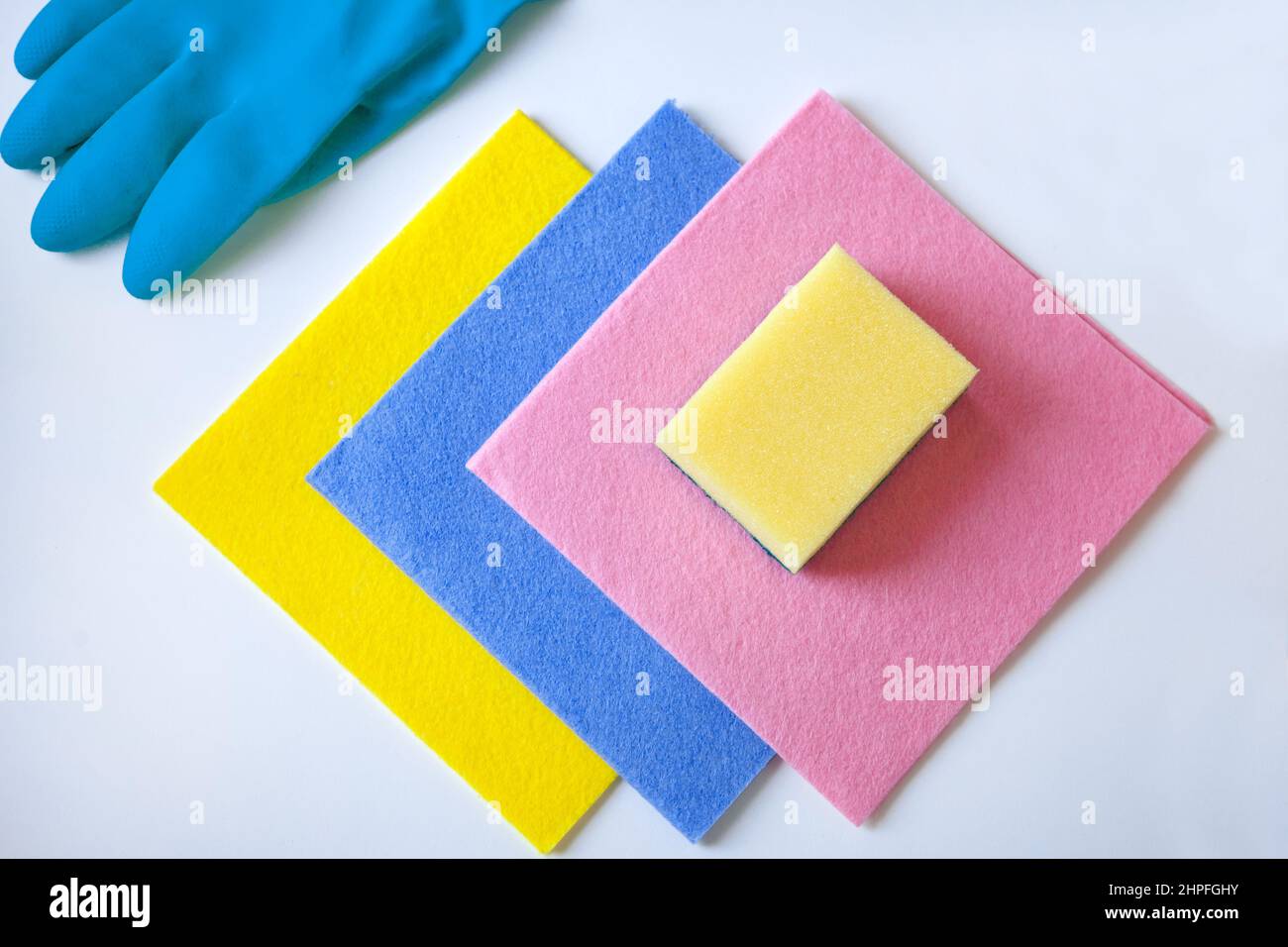panni per la pulizia e spugne colorate con guanti, guanti in gomma per la pulizia su sfondo bianco, posa piatta. Foto Stock