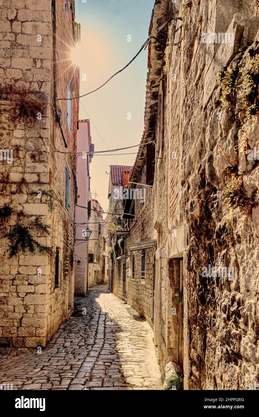 Case in pietra e lampione in stretta strada posteriore di Trogir, Croazia Foto Stock