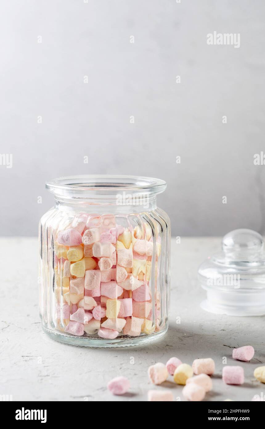 Marshmallow color pastello in vaso di vetro su sfondo grigio. Messa a fuoco selettiva. Foto Stock