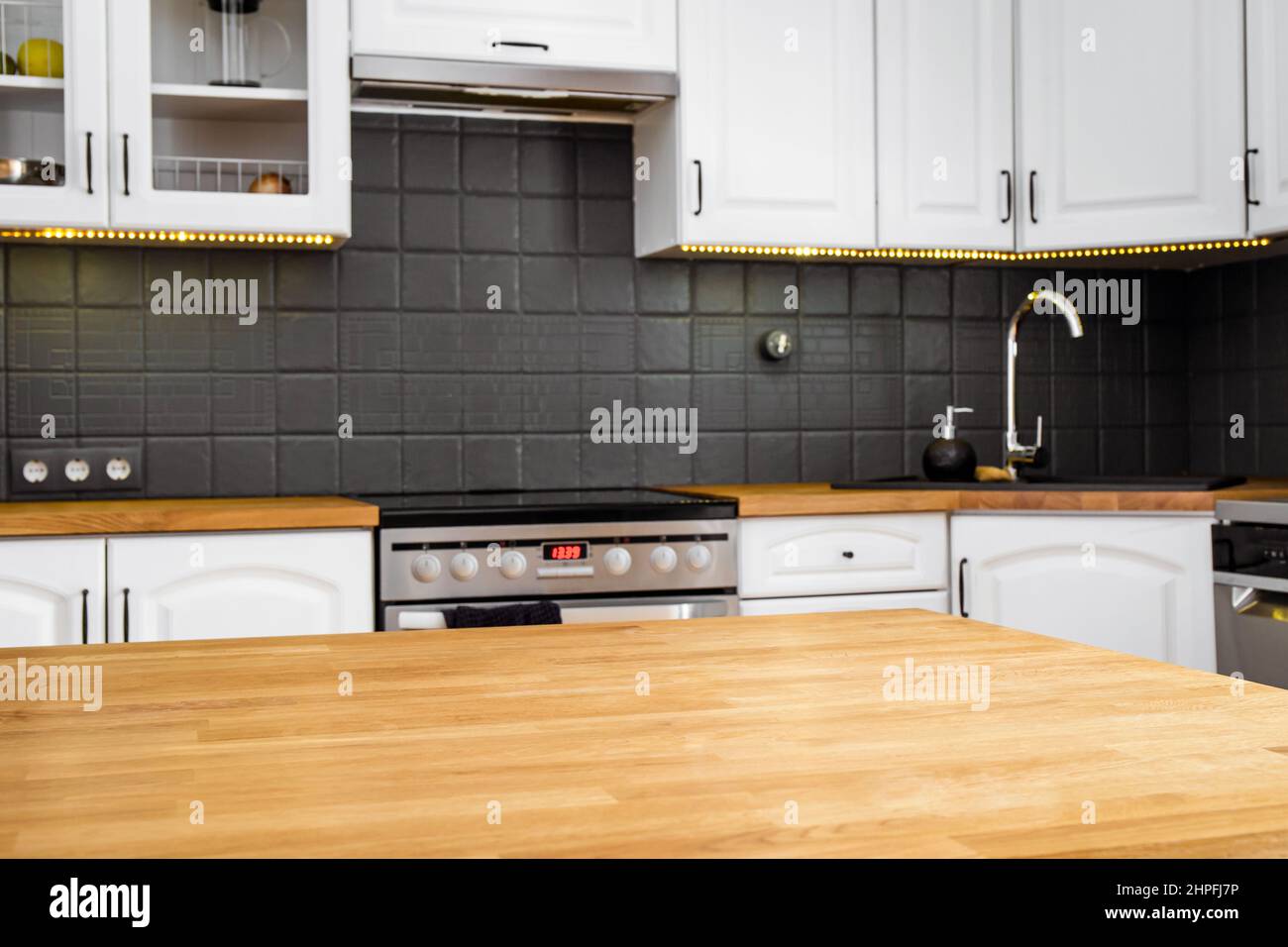 Moderno angolo cottura a casa di colore bianco con piano di lavoro in legno di quercia di colore naturale e vari elettrodomestici. Foto Stock