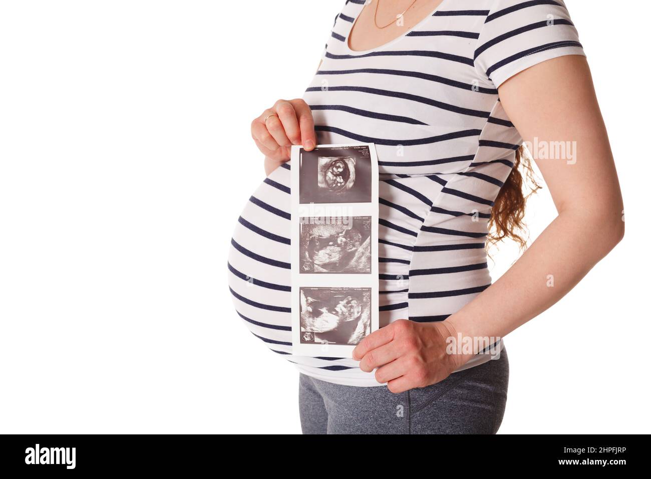 Donna incinta in piedi e tenendo la sua scansione del bambino a ultrasuoni Foto Stock