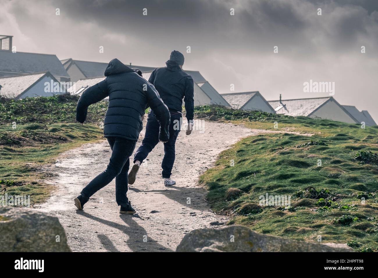 Persone che lottano per camminare lungo un sentiero costiero in tempesta vento forza portato da Storm Eunice come arriva a Newquay in Cornovaglia. Foto Stock