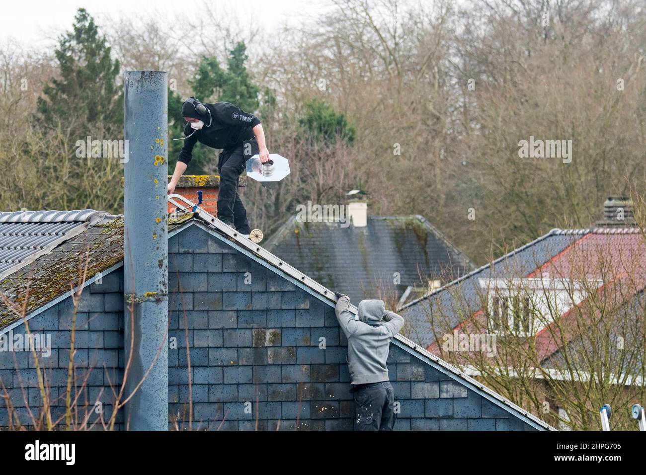 Coperture / coperture appaltatori che lavorano sul tetto per lavori di riparazione in una giornata di tempesta dopo il passaggio di tempeste Eunice e Franklin nel febbraio 2022 Foto Stock