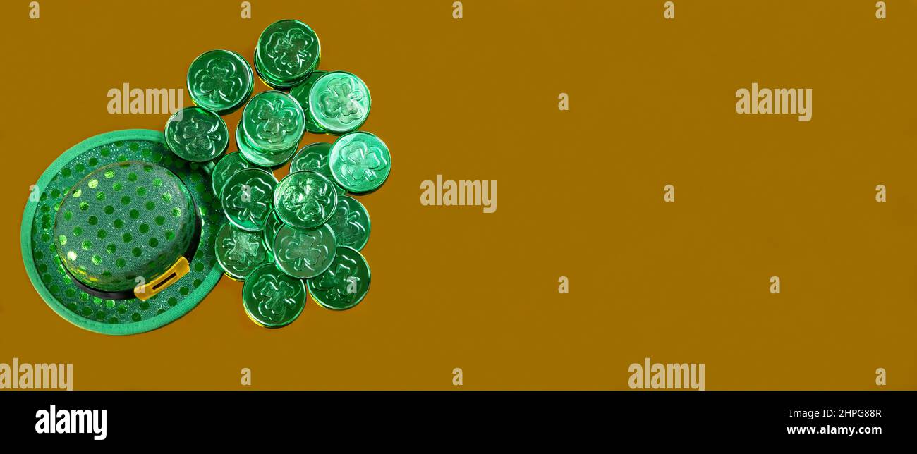 Cappello irlandese fortunato e monete verdi per il giorno di San Patrizio su sfondo dorato in formato vista dall'alto Foto Stock