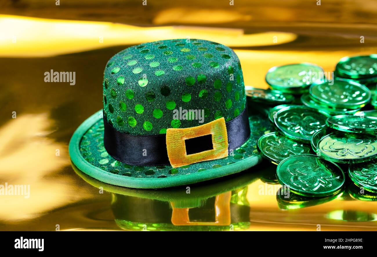 Cappello di buona fortuna e monete verdi per San Patricks Day su sfondo dorato Foto Stock