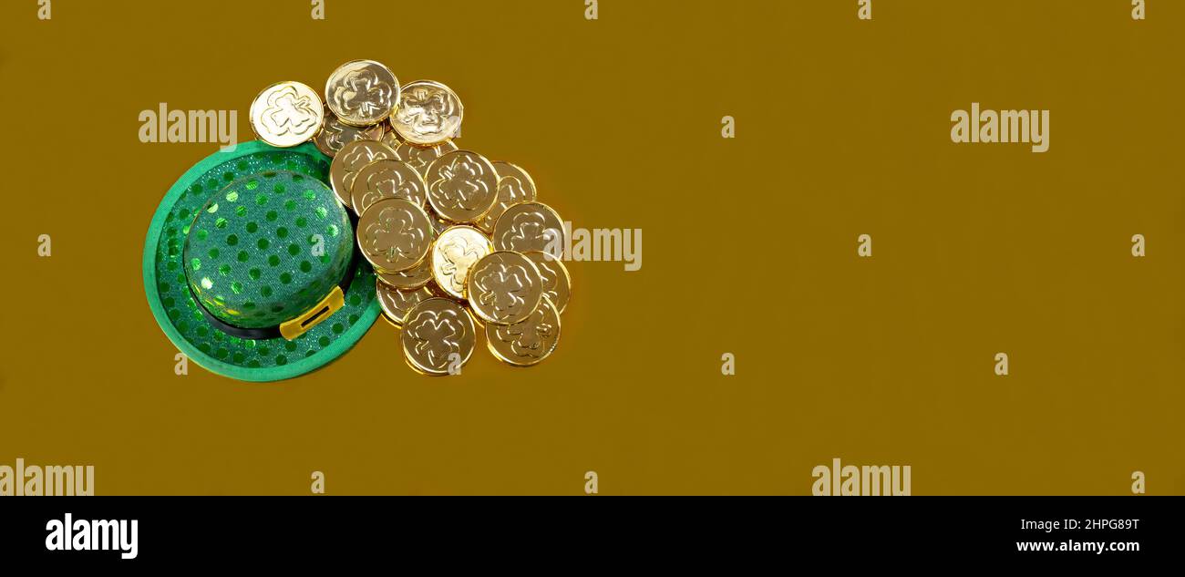 Cappello verde e monete d'oro per San Patrizio su sfondo dorato in formato vista dall'alto Foto Stock