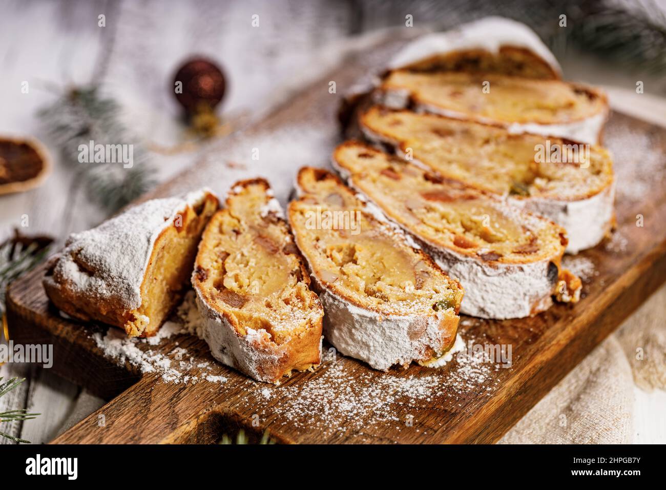 Stollen di Natale su un tagliere. Sfondo bianco tavolo in legno. Tradizionale dolce natalizio con marzapane, noci, uvetta e frutta secca. Foto Stock