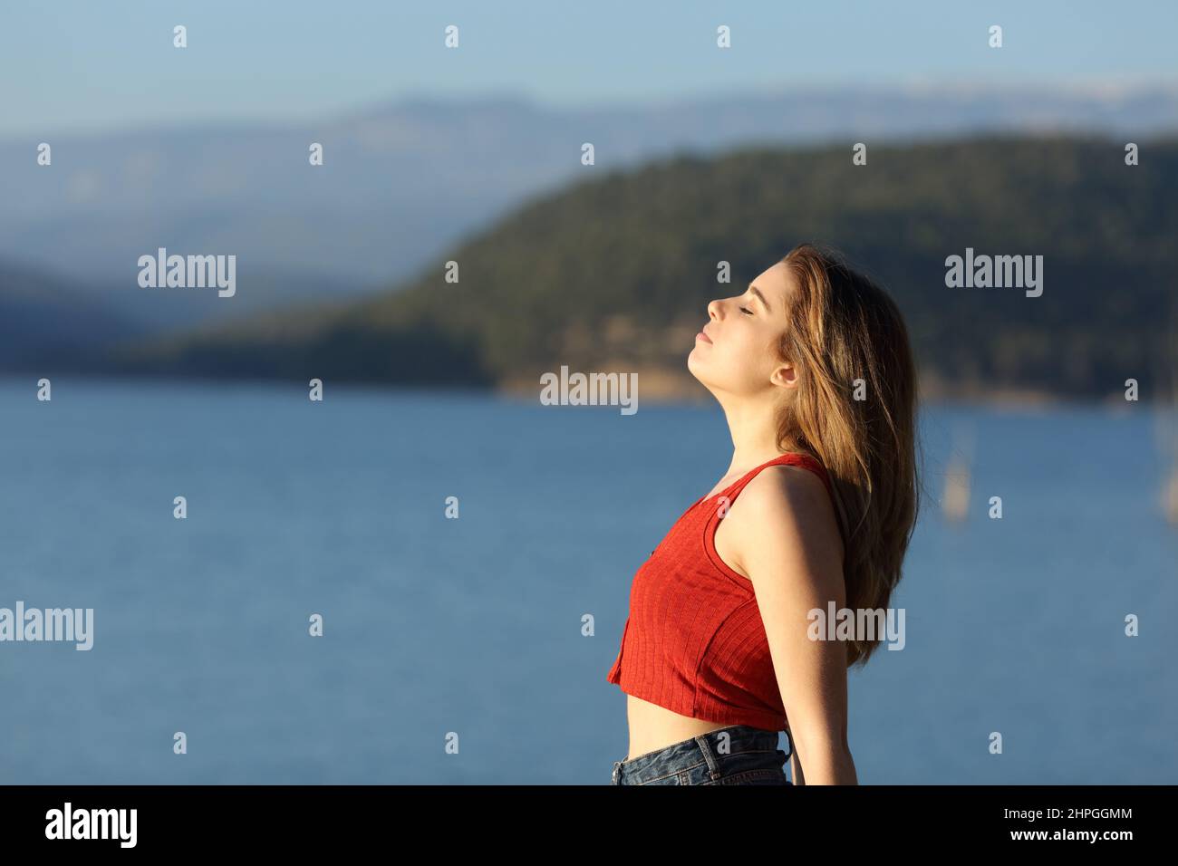 Vista laterale ritratto di un teen in rosso respirando aria fresca in un lago Foto Stock