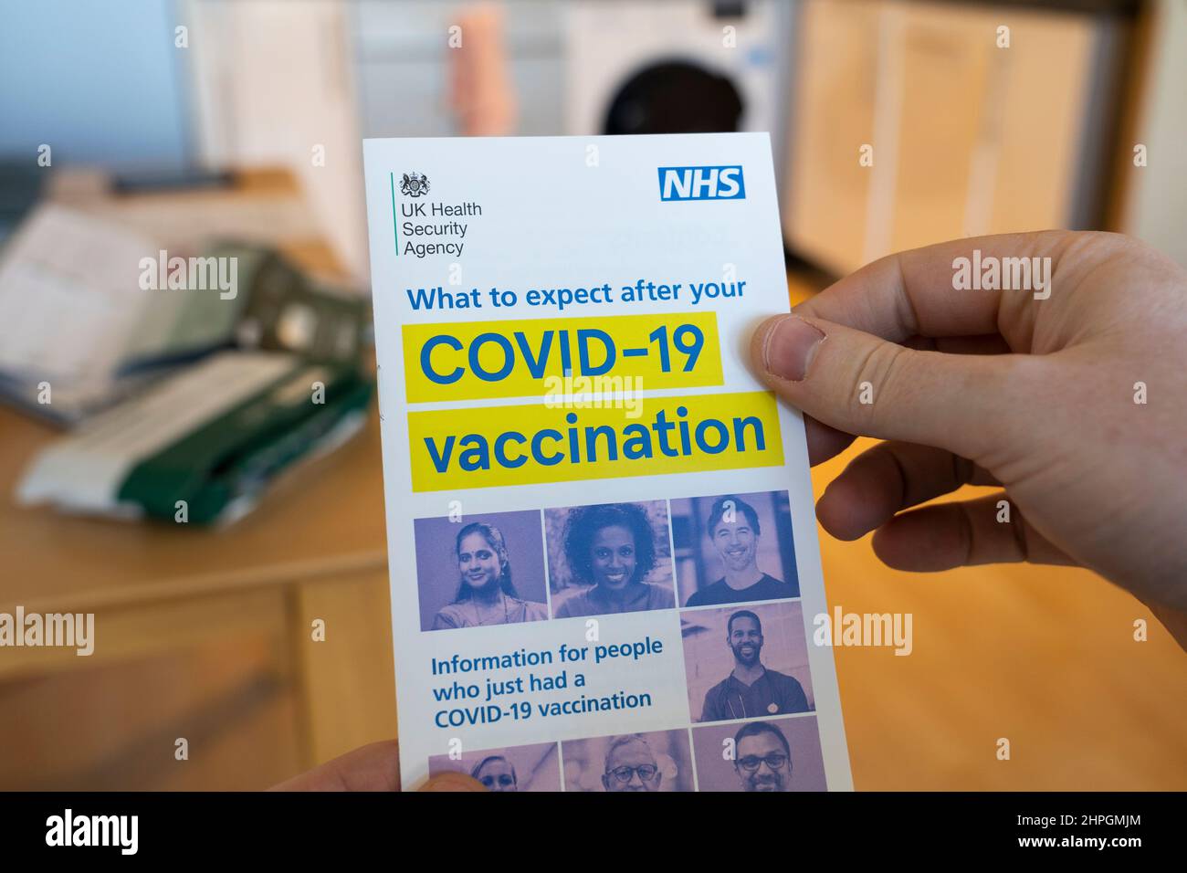 Le mani di un uomo che tiene un'agenzia di sicurezza del governo del Regno Unito e un opuscolo NHS che fornisce consigli su cosa accade dopo una vaccinazione di Coronavirus Covid-19 Foto Stock