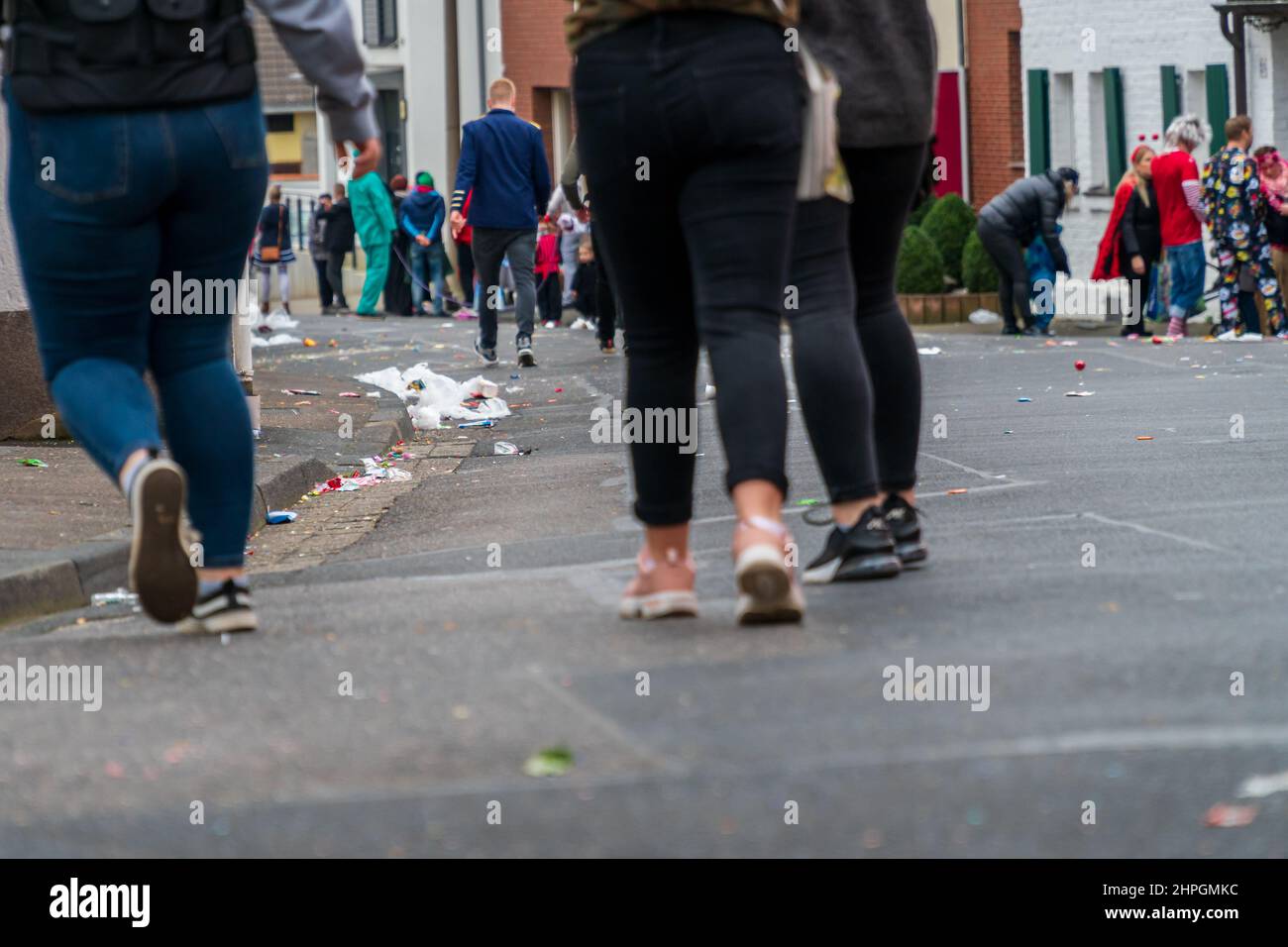 Bornheim, Renania settentrionale-Vestfalia, Germania - 22 febbraio 2020: Persone che camminano lungo una strada, gettato di rifiuti, dopo una sfilata di carnevale. Foto Stock