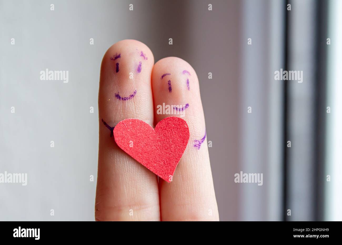 Volti sorridenti disegnati sulle dita. Felice coppia abbracciante. Foto di sfondo del giorno di San Valentino. Foto Stock