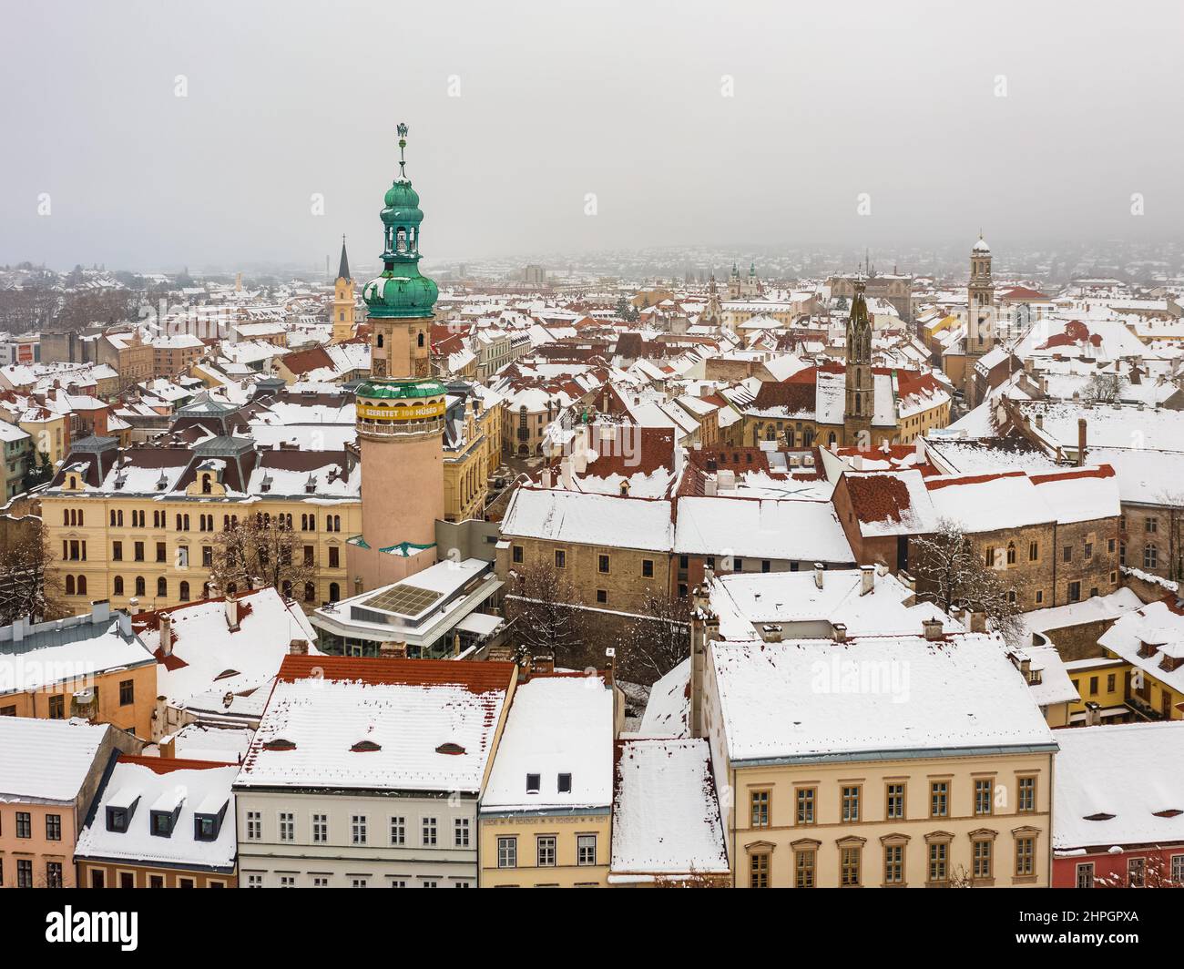 Vista aerea sull'iconica torre dei vigili del fuoco e sul municipio di Sopron nel cuore della città. Il nome ungherese è Tűztorony. Paesaggio urbano invernale tetti innevati. Foto Stock