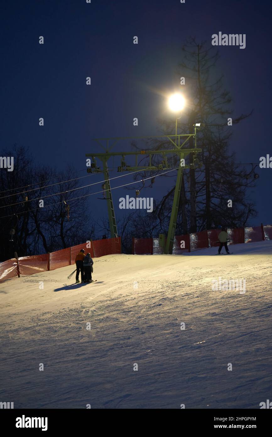 Treffelhausen, Germania - 28 gennaio 2022: Skilift in funzione di notte con illuminazione. Atleti d'inverno sulle piste nella neve. Esposizione prolungata Foto Stock