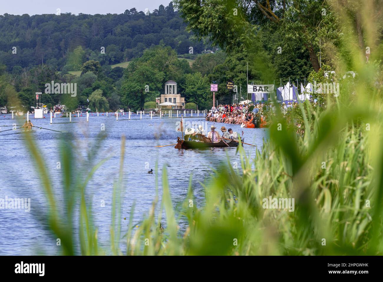 Il Tamigi con Temple Island in lontananza. Folle di spettatori costeggiano la riva del fiume per guardare la famosa regata di canottaggio. Henley-on-Thames, Inghilterra Foto Stock