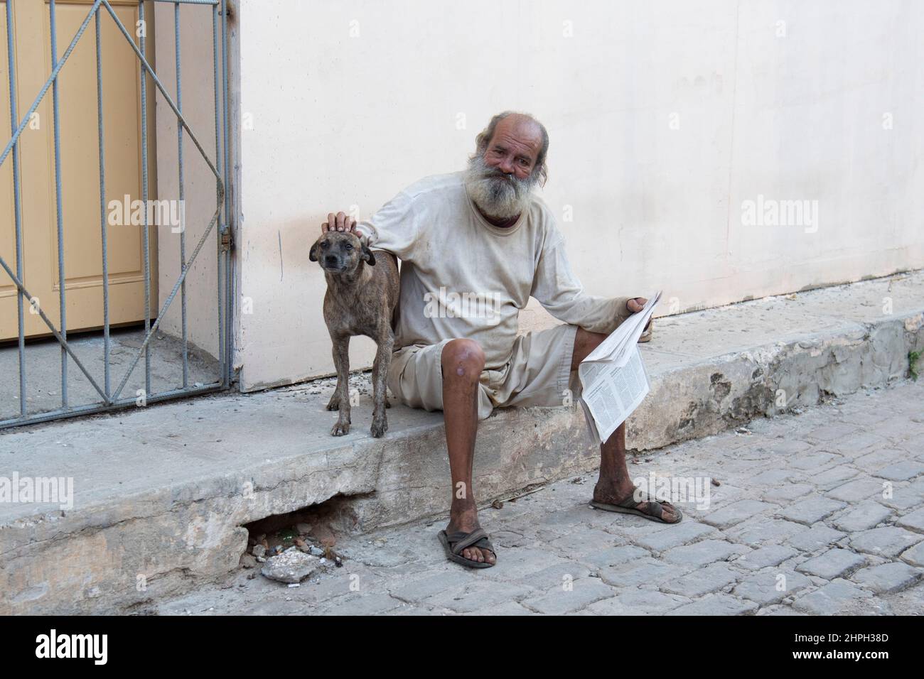 L'uomo che tiene il giornale ruba la testa del suo cane da compagnia su una strada a l'Avana, Cuba. Foto Stock