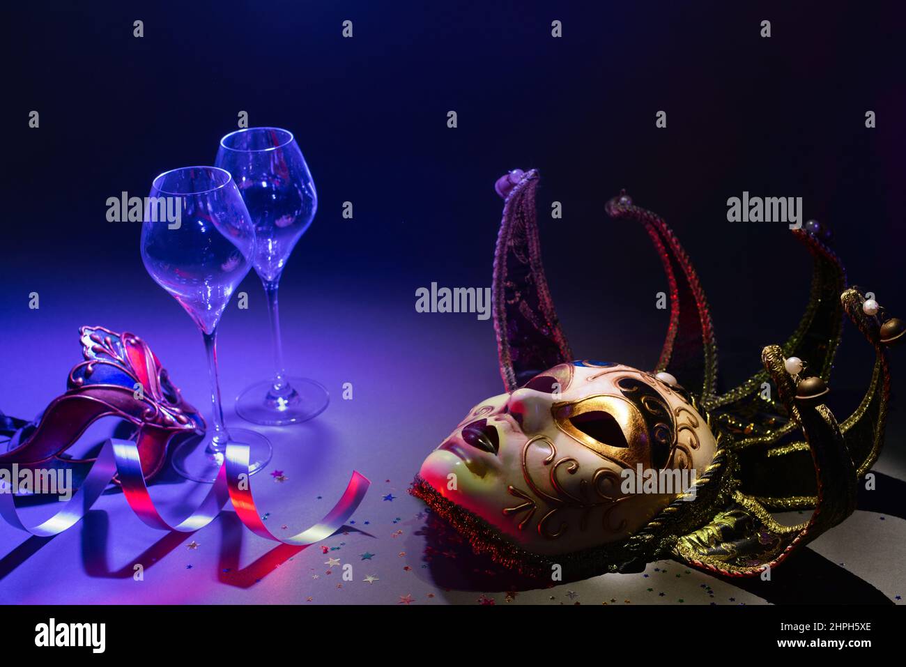 Maschere veneziane di carnevale con bicchieri da champagne e nastri in ambiente scuro Foto Stock