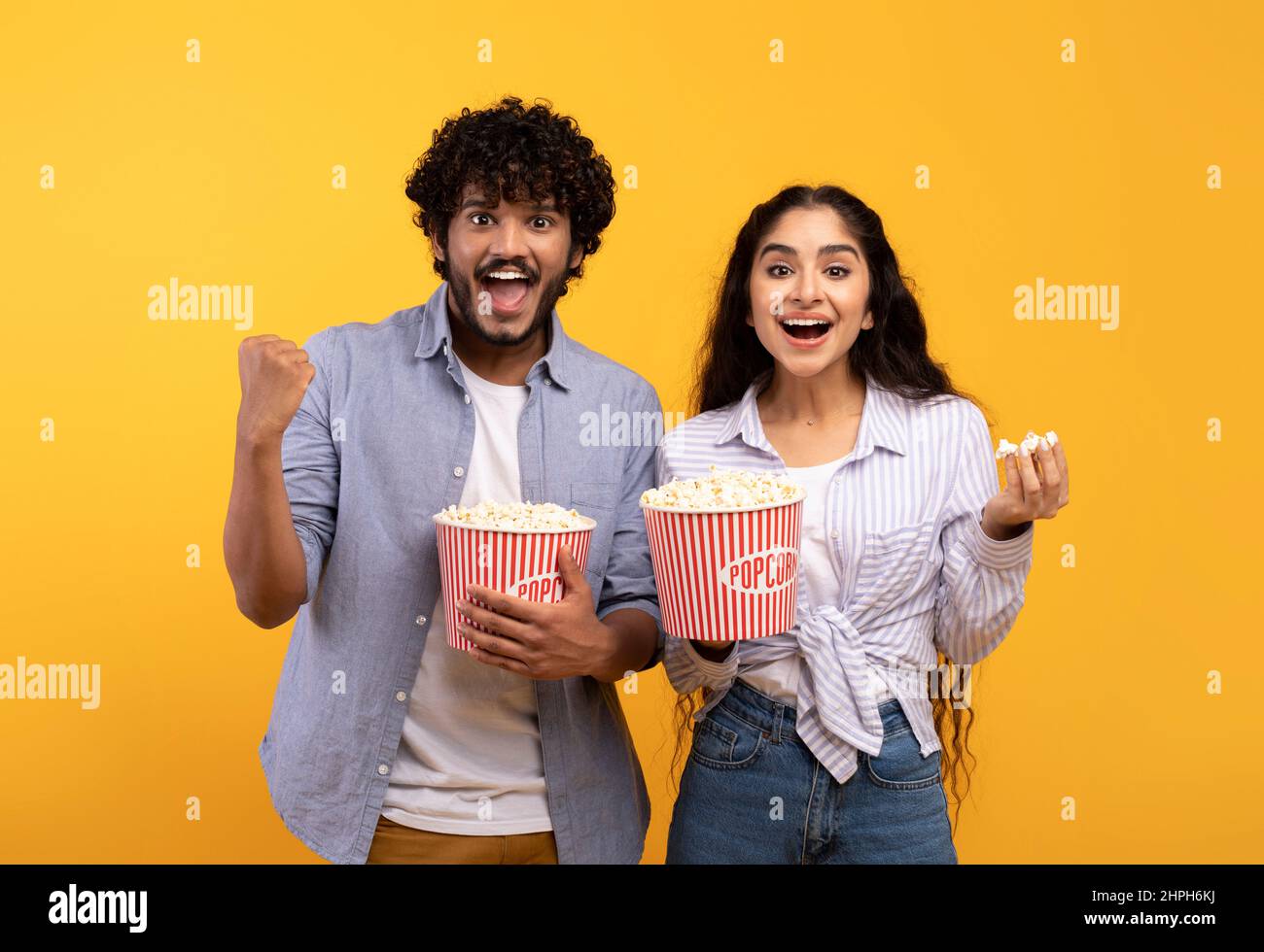L'uomo e la donna indiani eccitati mangiano popcorn, guardano film o partite di calcio, celebrando il successo della loro squadra Foto Stock
