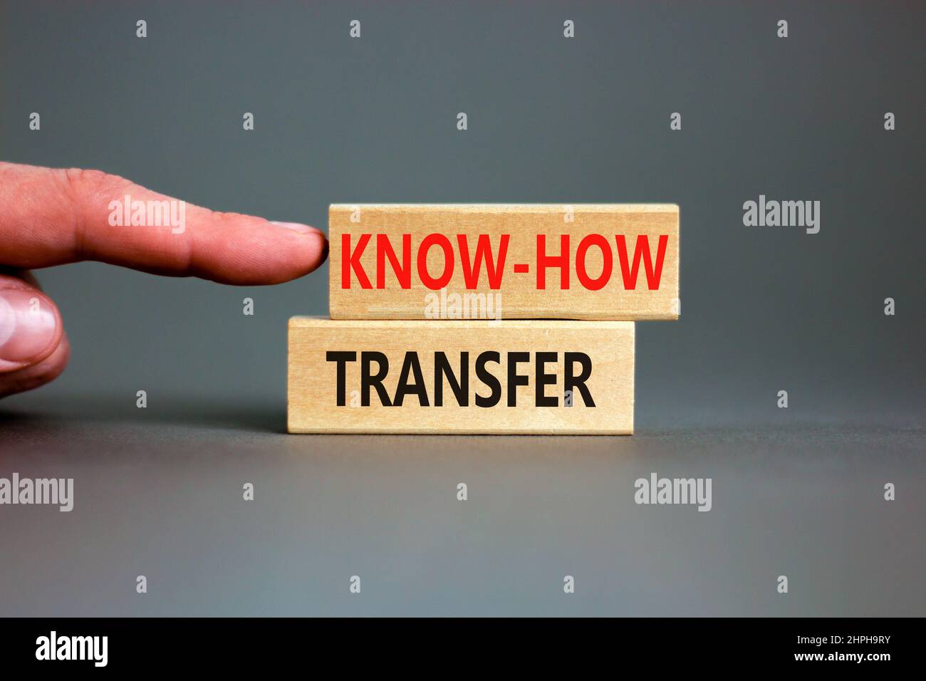Simbolo di trasferimento del know-how. Concetto parole know-how trasferimento su blocchi di legno su bello grigio tabella sfondo grigio. Mano dell'uomo d'affari. Spazio di copia. Busi Foto Stock