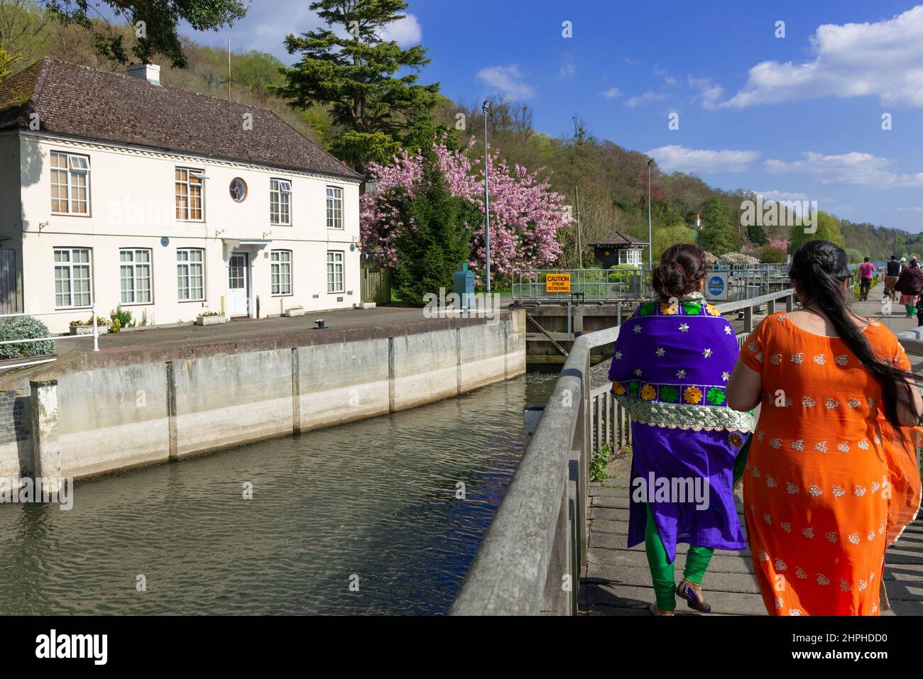Due donne che indossano la Saris fanno una passeggiata lungo il ponte di legno fino a Marsh Lock sul Tamigi a Henley-on-Thames, Oxfordshire, Inghilterra, Regno Unito Foto Stock