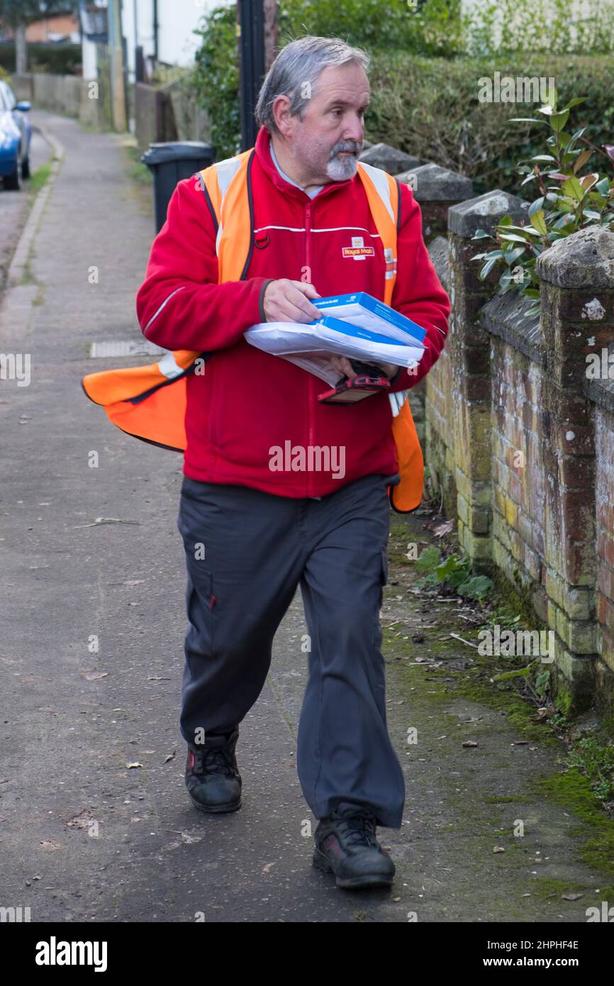 Postman consegna lettere e test di flusso laterale in un villaggio di Suffolk, Regno Unito. Foto Stock