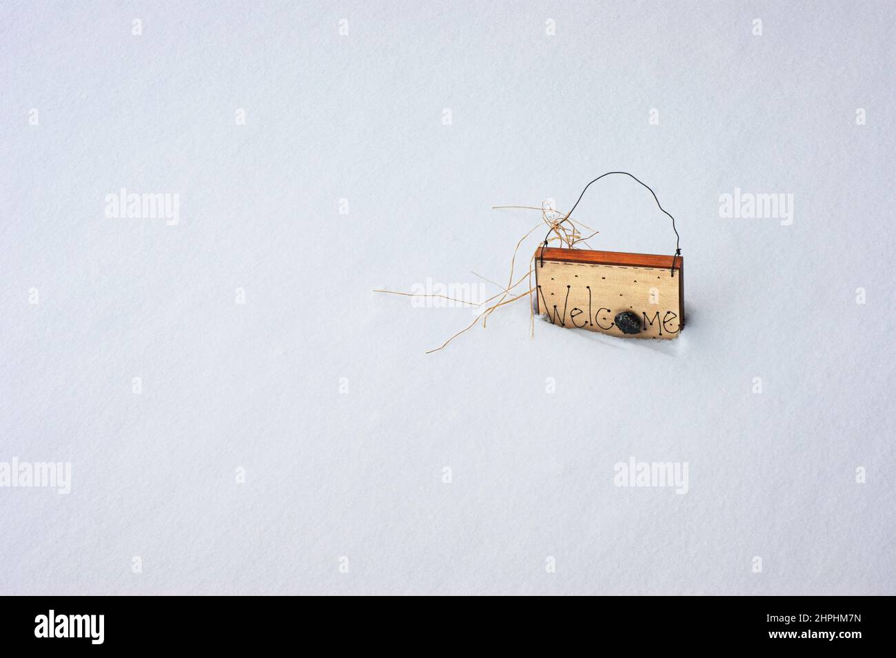 Cartello di benvenuto circondato e affondato in una fresca e pulita banca di neve bianca. Il cartello in legno verniciato ha una maniglia in filo. È disponibile uno spazio per i messaggi di testo. Foto Stock