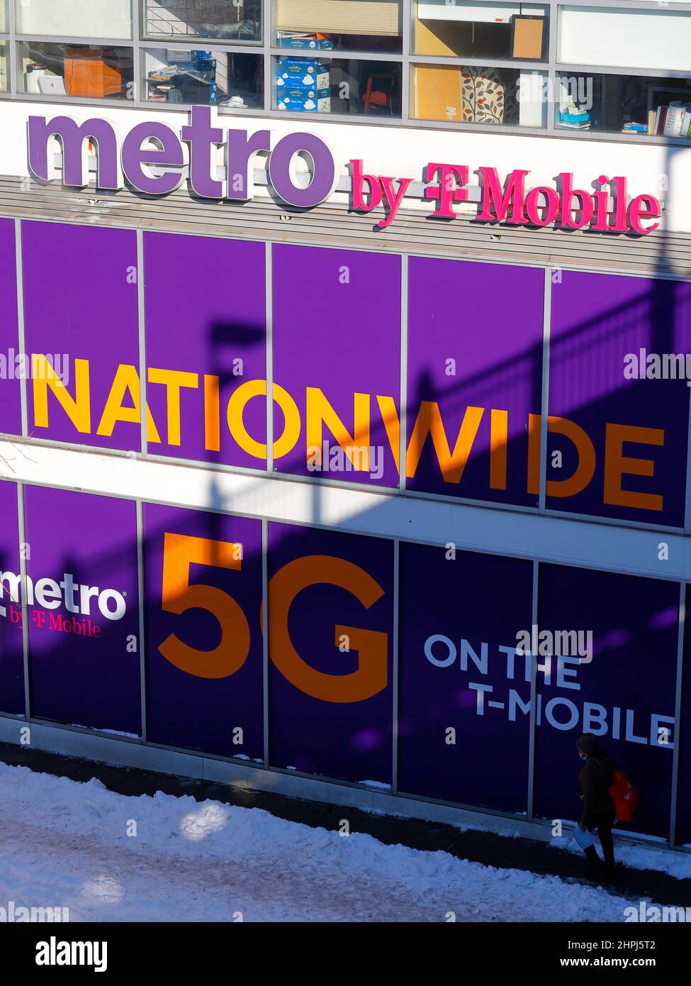 Una persona cammina davanti a una metro da T-Mobile negozio di cellulari con grande segnaletica che annuncia a livello nazionale 5G, New York, NY. Foto Stock