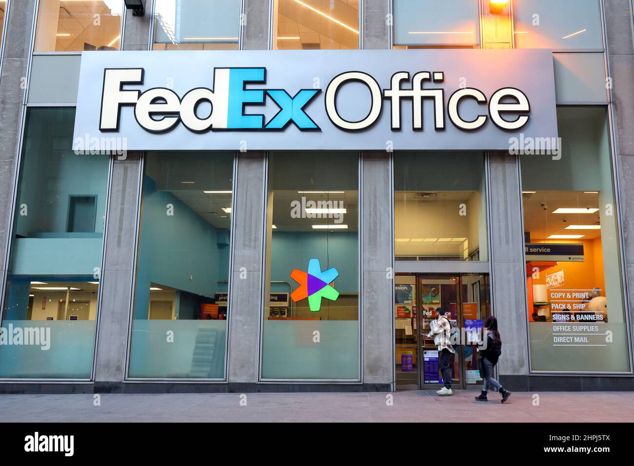 FedEx Office, 125 W 47th St, New York, NY. Il gigantesco logo di una società di stampa e spedizione logistica si affaccia sugli acquirenti nel Midtown Manhattan. Foto Stock