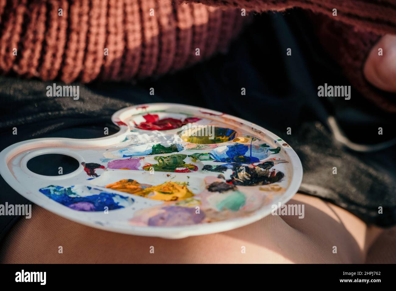 Le mani di una donna che mescolano le vernici su una tavola della tavolozza. Preparazione alla verniciatura di un'immagine. Strumenti artistici. Il processo creativo. Foto Stock