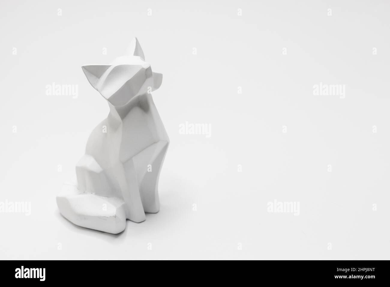 Statuina di gatto in stile origami con sfondo bianco Foto Stock
