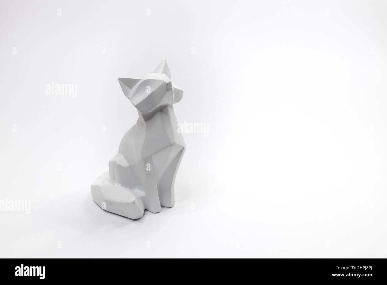 Statuina di gatto in stile origami con sfondo bianco Foto Stock