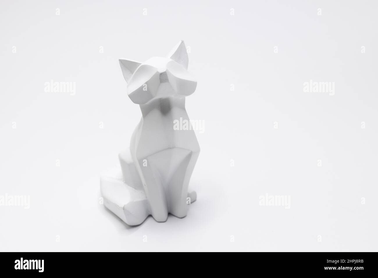 Una statuina di gatto in stile origami con sfondo bianco Foto Stock