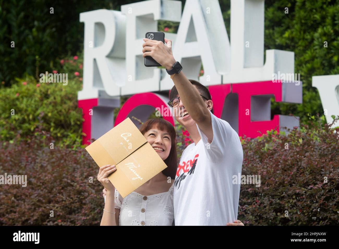 Singapore. 22nd Feb 2022. Una coppia sposata di recente prende selfie a Fort Canning Park, dopo la registrazione del matrimonio al vicino Registro delle nozze di Singapore il 22 febbraio 2022. 22 febbraio del 2022, una data con numeri di 2s che circa risuonano la pronuncia di 'amore' in cinese parlato, è preferito dalle coppie di registrare il matrimonio per i buoni desideri. Credit: Allora Chih Wey/Xinhua/Alamy Live News Foto Stock