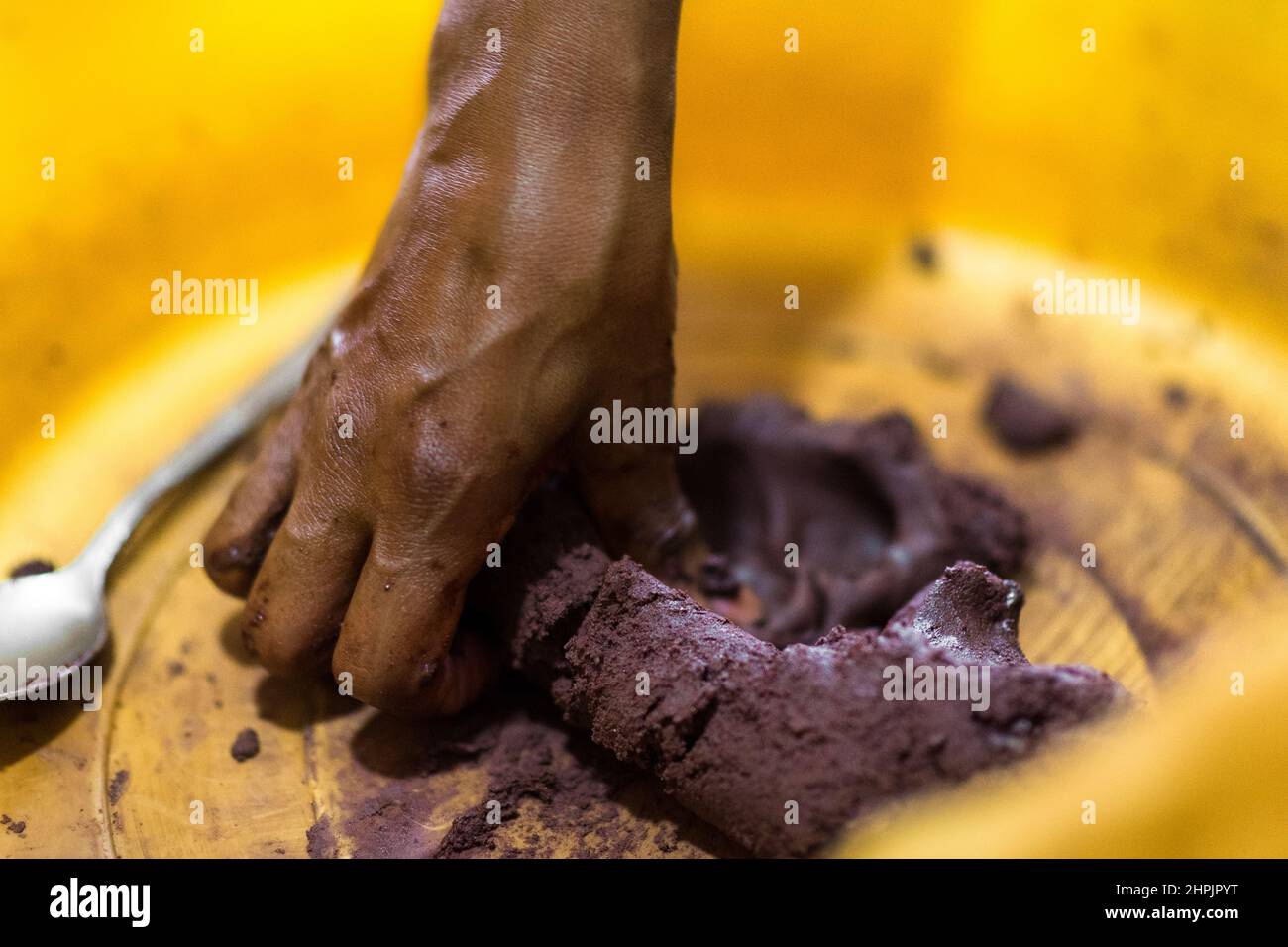 Una donna afro-colombiana inginocchia la pasta di cacao crudo prima di stendersi le palle di cioccolato nella lavorazione artigianale del cioccolato a Cuernavaca, Colombia. Foto Stock