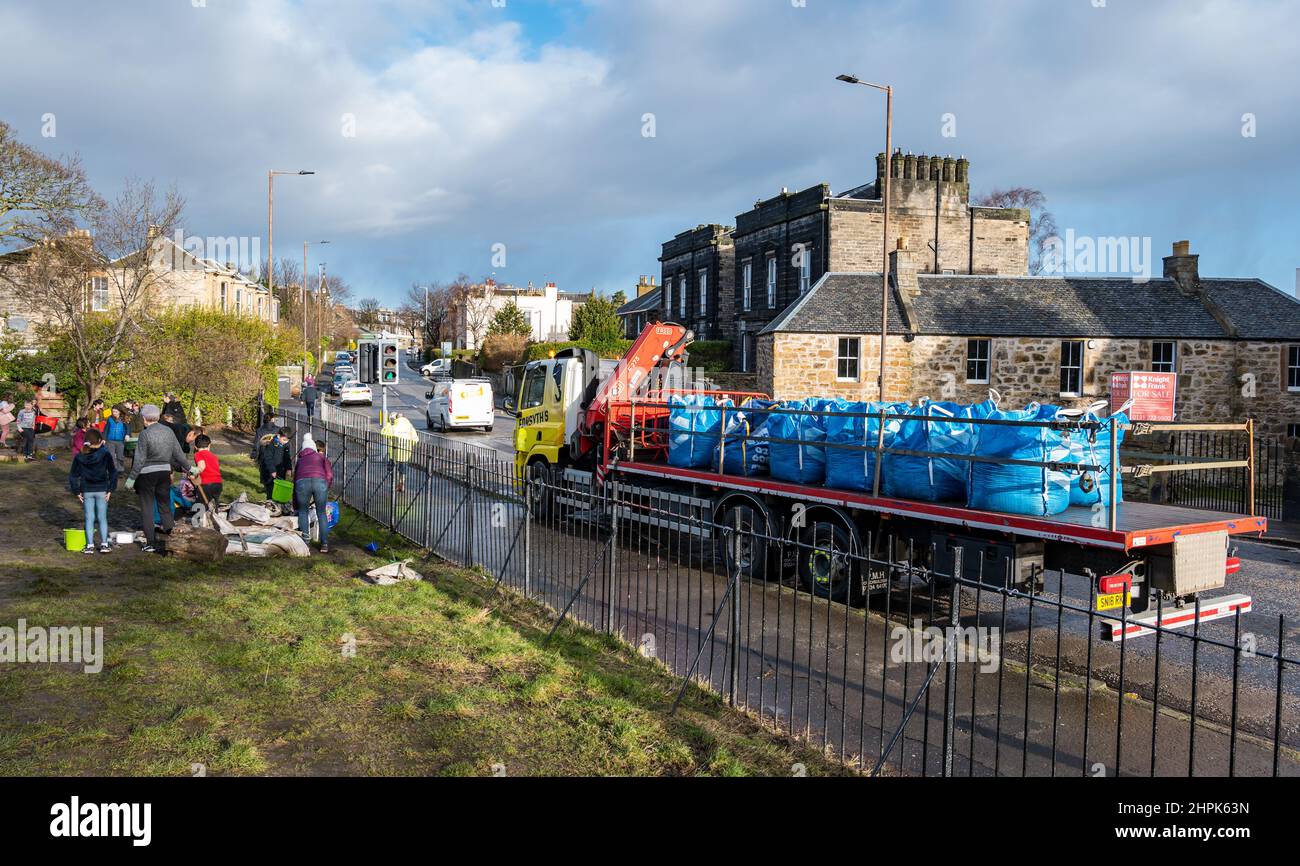 Trinity Primary School, Edimburgo, Scozia, Regno Unito, 22 febbraio 2022. Topsoil Botanico per le scuole: Scavo durante il Royal Botanic Garden Biomes Project risulta in un'eccedenza di 50 tonnellate di topsoil che è dato alle scuole, allotments & organizzazioni della comunità dalla società di costruzione Balfour Beatty. Una consegna di 5 tonnellate avviene presso la Trinity Primary School per trasportare il suolo o la terra per riempire piantatrici nel giardino della scuola per gli allievi per coltivare le verdure. Gli allievi primari 4 usano contenitori di tutte le forme e dimensioni per spostare la terra per riempire le piantatrici; lavoro di squadra è richiesto Foto Stock