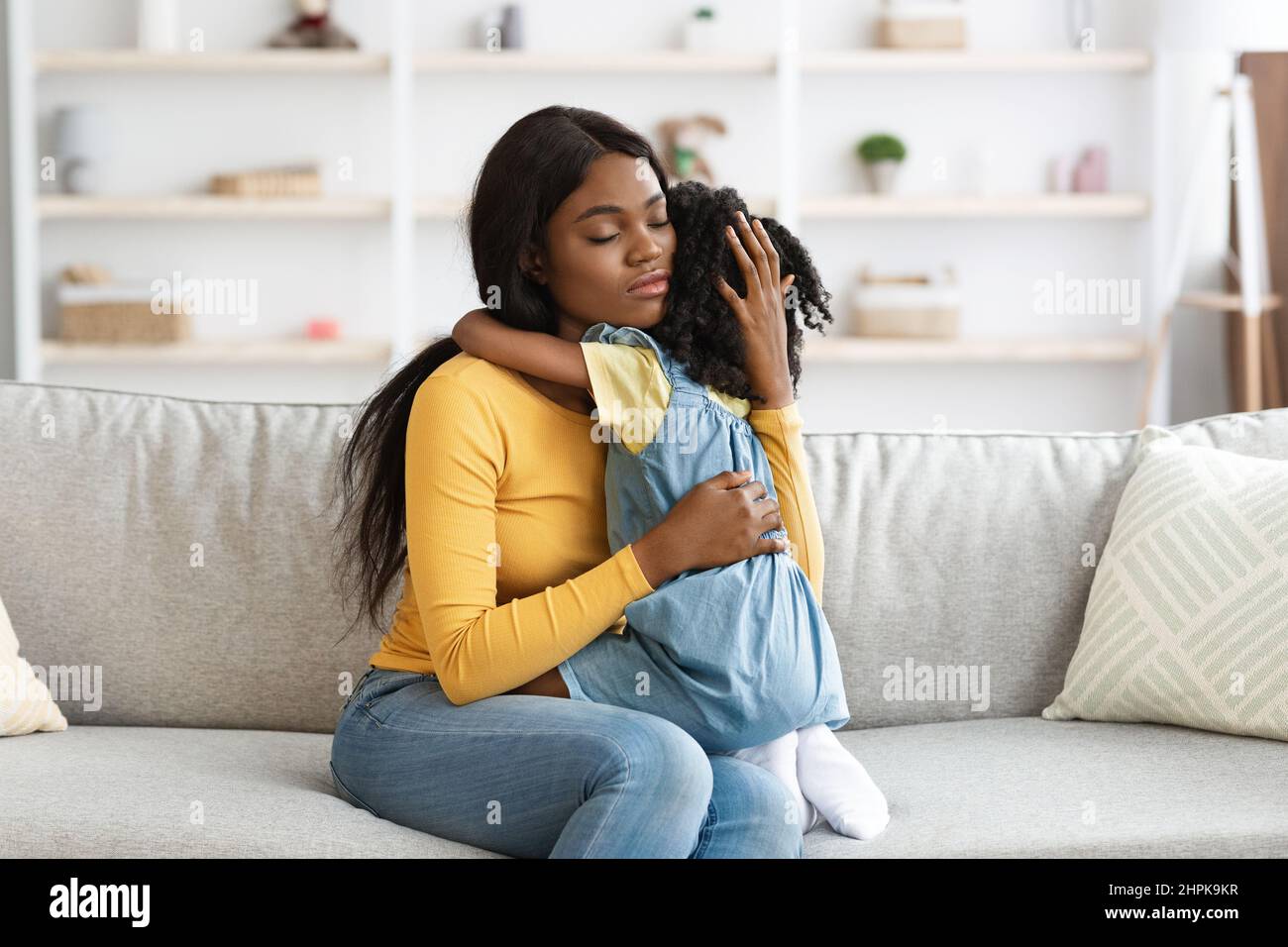 Cura della mamma afroamericana confortante figlia piccola sconvolta a casa Foto Stock