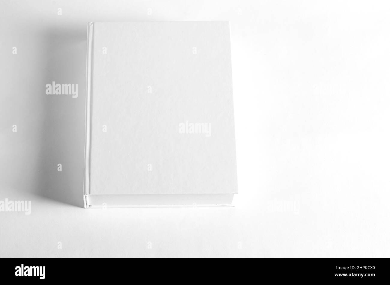 Mockup di libro quadrato chiuso su sfondo di carta testurizzata bianco. Sfondo parete Foto Stock